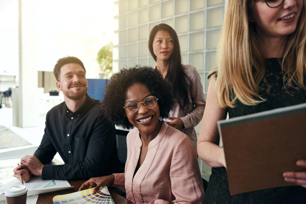 Team of colleagues smiling and engaging together, symbolizing how soft skills training builds trust, understanding, and collaboration to prevent miscommunication and workplace tension.