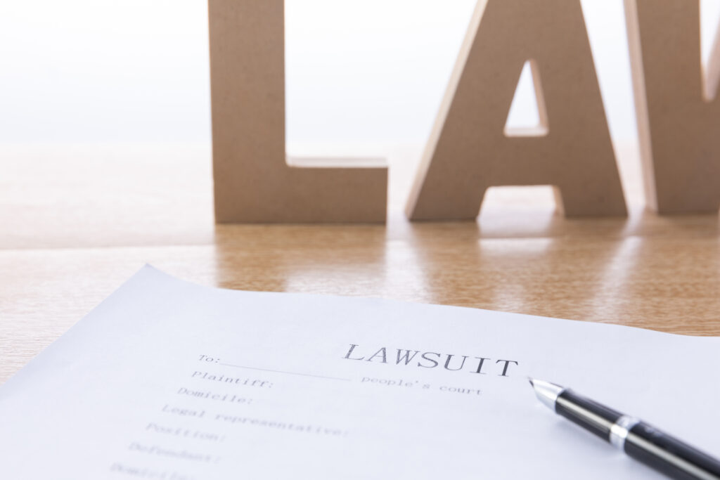 Lawsuit document with a pen on a desk, symbolizing the costly HR mistakes businesses face when compliance issues go unnoticed until an audit or legal claim.