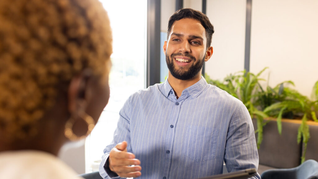 Smiling professional greeting a colleague, symbolizing trusted HR partnership, proactive guidance, and personalized support that strengthens culture and business growth.
