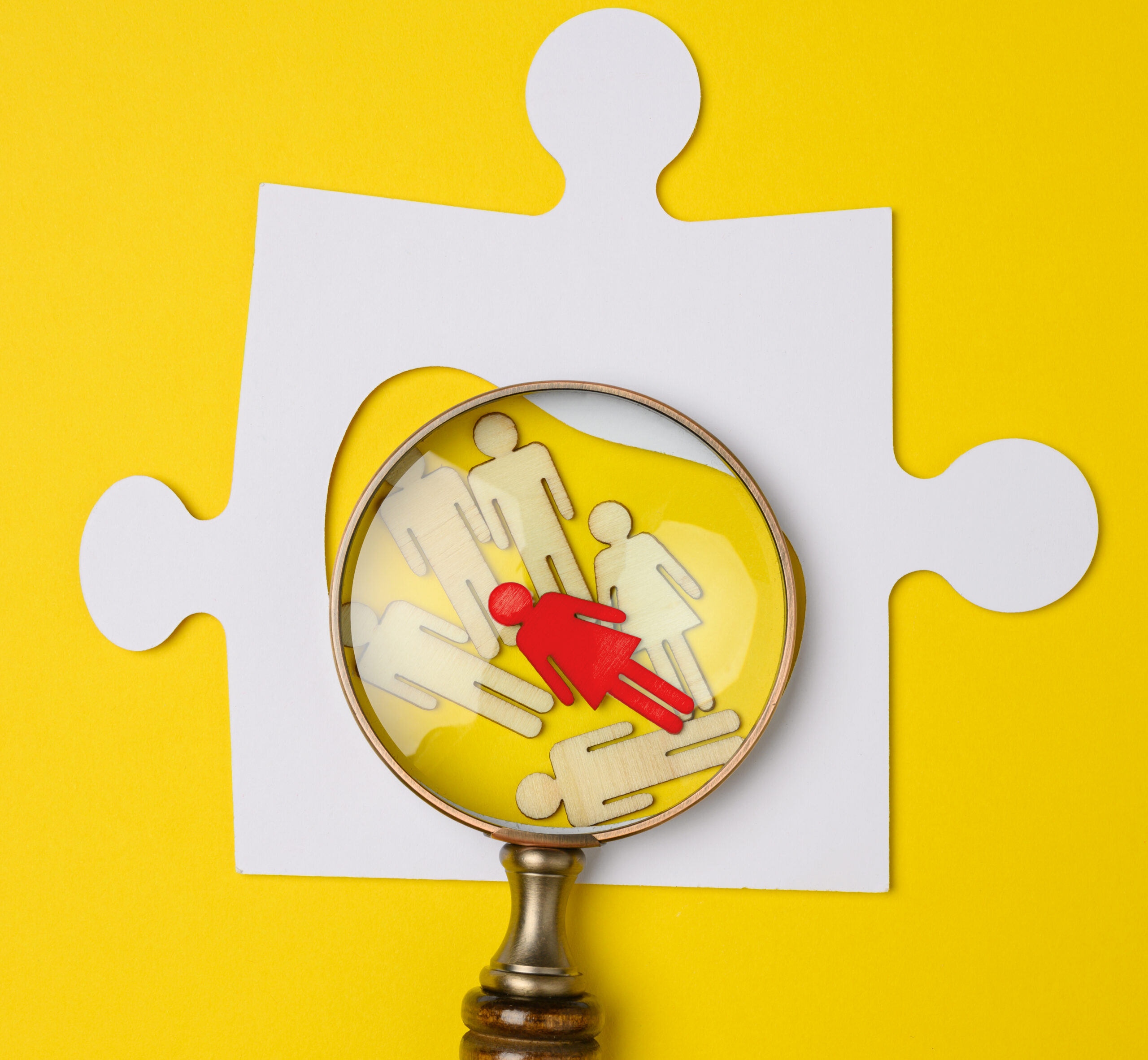 Magnifying glass highlighting a red figure among wooden people icons, symbolizing confidential, compliant, and unbiased workplace investigations including harassment, retaliation, and code of conduct violations.